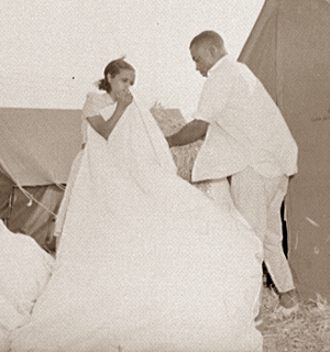 Man and woman stuffing straw into cloth bag outdoors